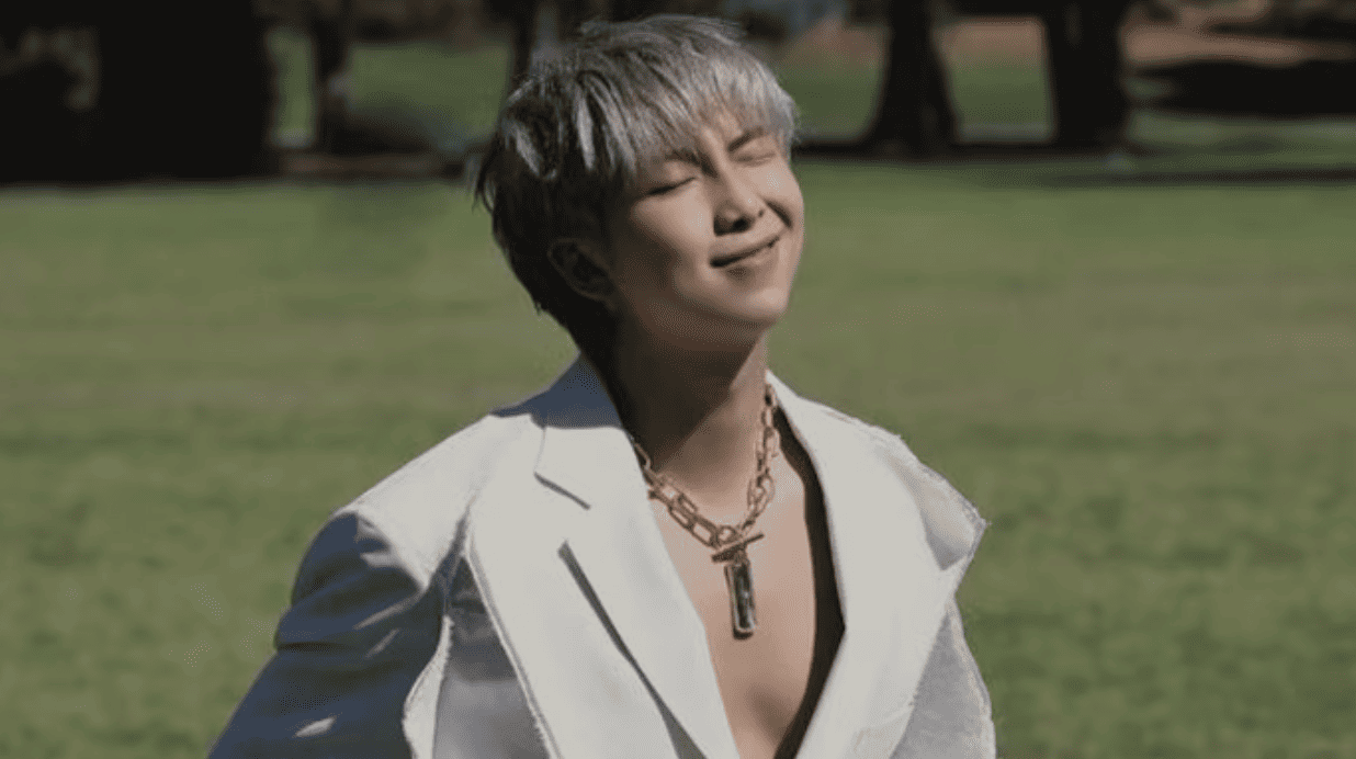 RM in a white blazer posing under sunlight